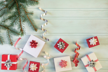 Christmas composition of red and white gift boxes, bows and ribbons. A branch of the Christmas tree. Place for text, copy space.