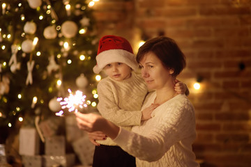 Mother or grandmother with her little son or grandson celebration Christmas with sparkler