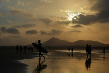 silhouette of surfer getting out from the water at sunset