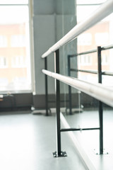 Background image view along of ballet bar in empty dance class lit by serene light, copy space
