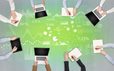 Group of people with devices in hands teamworking on laptops, tablets and prepare report with chart...