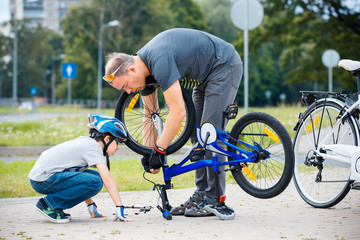 Cute little boy with his father repairing bicycle outdoors - 226415474