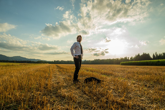 Young confident businessman standing in sawn field