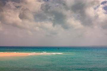 Tanzania. Stone town. Prison island. The white sand the tongue of land in turquoise blue sea and cloudy sky.