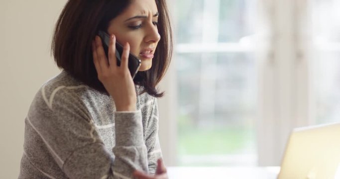 4K Unhappy Asian businesswoman in sunny office dealing with a problem over the phone. Slow motion.