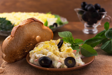 Salad of sliced boiled eggs, crab meat with cheese and cucumber, basil  leaves, chopped marinated black olives, toasted toast.
