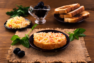 A quick Breakfast of bread with crab meat and grated cheese baked in the oven, basil leaves and pickled olives.