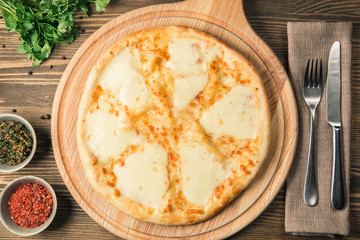 Four cheese pizza quattro fromaggi with basil leaf on a rustic wooden board background
