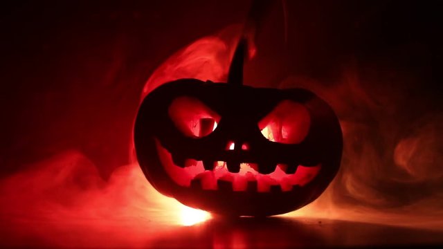 Halloween pumpkin smile and scrary eyes for party night. Close up view of scary Halloween pumpkin with eyes glowing inside at black background. Selective focus