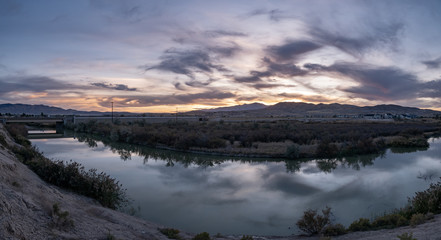 Banner panorama of a dark sunset with clouds reflecting off the river