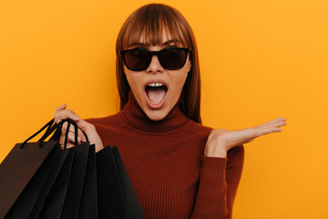 Black friday. Shopping. Woman portrait. Girl in sun glasses is holding shopping bags and looking at...