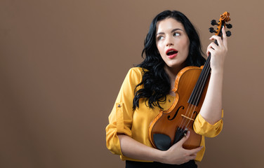 Young woman with a violin on a brown background