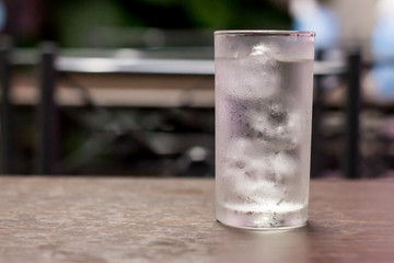 Put a glass of water on a wooden table.