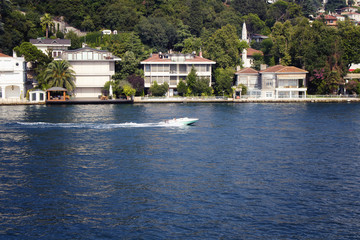 Fototapeta na wymiar View of small motorboat on Bosphorus, houses on Asian side of Istanbul. It is a sunny summer day.