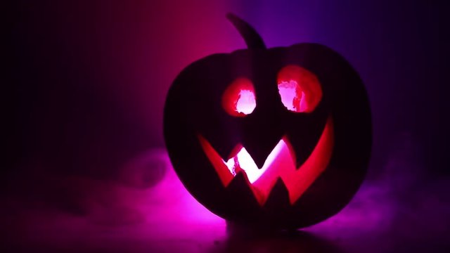 Halloween pumpkin smile and scrary eyes for party night. Close up view of scary Halloween pumpkin with eyes glowing inside at black background. Selective focus