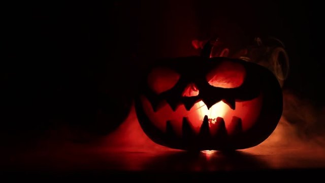 Halloween pumpkin smile and scrary eyes for party night. Close up view of scary Halloween pumpkin with eyes glowing inside at black background. Selective focus