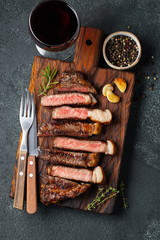 Sliced steak Striploin, grilled with pepper, garlic, salt and thyme served on a wooden chopping...