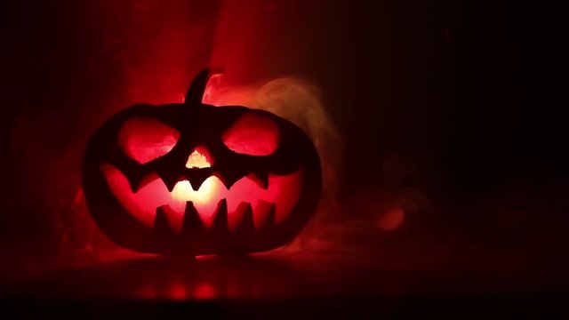 Halloween pumpkin smile and scrary eyes for party night. Close up view of scary Halloween pumpkin with eyes glowing inside at black background. Selective focus