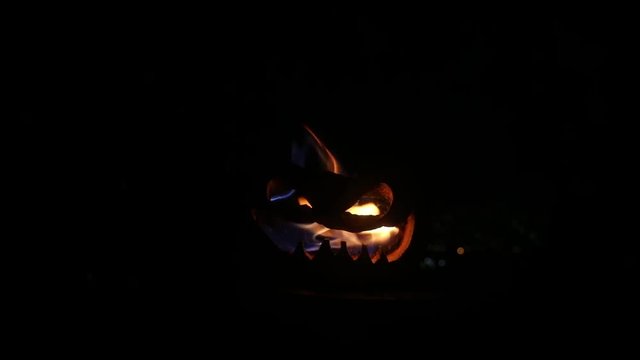 Halloween pumpkin smile and scrary eyes for party night. Close up view of scary Halloween pumpkin with eyes glowing inside at black background. Selective focus