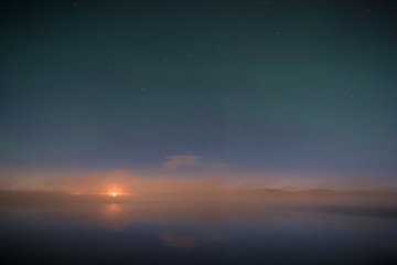 Faint northern lights above the lake, wild fire in background