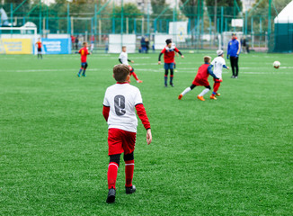football teams - boys in red, blue, white uniform play soccer on the green field. boys dribbling. dribbling skills. Team game, training, active lifestyle, hobby, sport for kids concept	