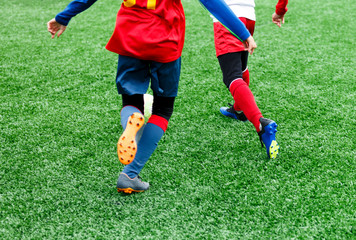 football teams - boys in red, blue, white uniform play soccer on the green field. boys dribbling. dribbling skills. Team game, training, active lifestyle, hobby, sport for kids concept	