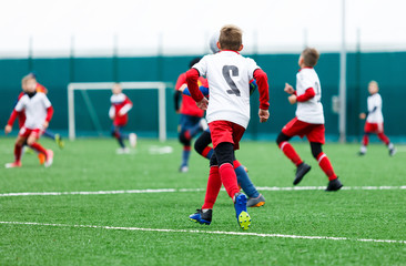 football teams - boys in red, blue, white uniform play soccer on the green field. boys dribbling. dribbling skills. Team game, training, active lifestyle, hobby, sport for kids concept	