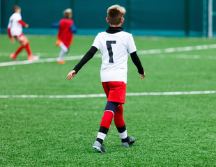 football teams - boys in red, blue, white uniform play soccer on the green field. boys dribbling. dribbling skills. Team game, training, active lifestyle, hobby, sport for kids concept	