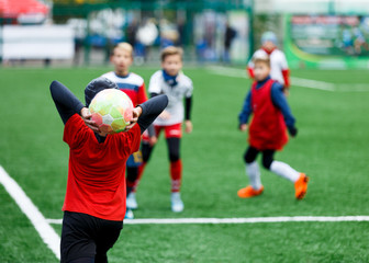 Obraz premium football teams - boys in red, blue, white uniform play soccer on the green field. boys dribbling. dribbling skills. Team game, training, active lifestyle, hobby, sport for kids concept 