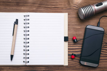 Mobile phone, blank page note pad, microphone and headphones on the table. Audio recording studio...