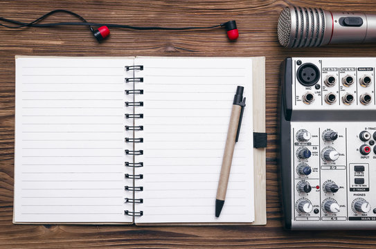 Audio recording studio concept. Karaoke. Song lyrics. Microphone, audio sound mixer, blank page notepad and headphones on the table.