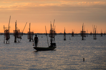 Fisherman on boat catching fish with sunset