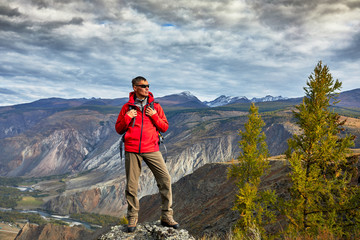 Young Man Traveler relaxing outdoor with backpack rocky mountains on background Autumn vacations and Lifestyle