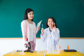 Asian schoolgirl and beautiful teacher standing and smile in school classroom