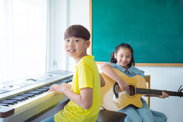 Happy Asian kids playing Music Instruments and smile In School classroom