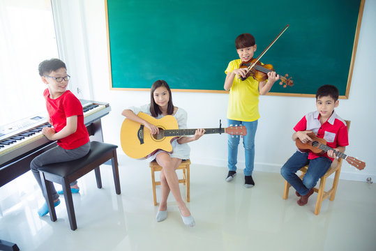 Group Of Happy Asian Kids Playing Music Instruments And Smile In School Classroom