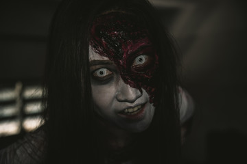 Asian female zombie standing in dark room and looking at camera