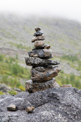 Pyramid of stones against the backdrop of a mountain pass. Stack of stones