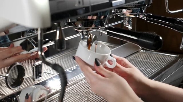 Coffee shop concept. Close up of female barista hands holding a cup at coffee making machine. Proccess of coffee making. hd