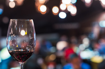 Glass of red wine against blurred bar with lights