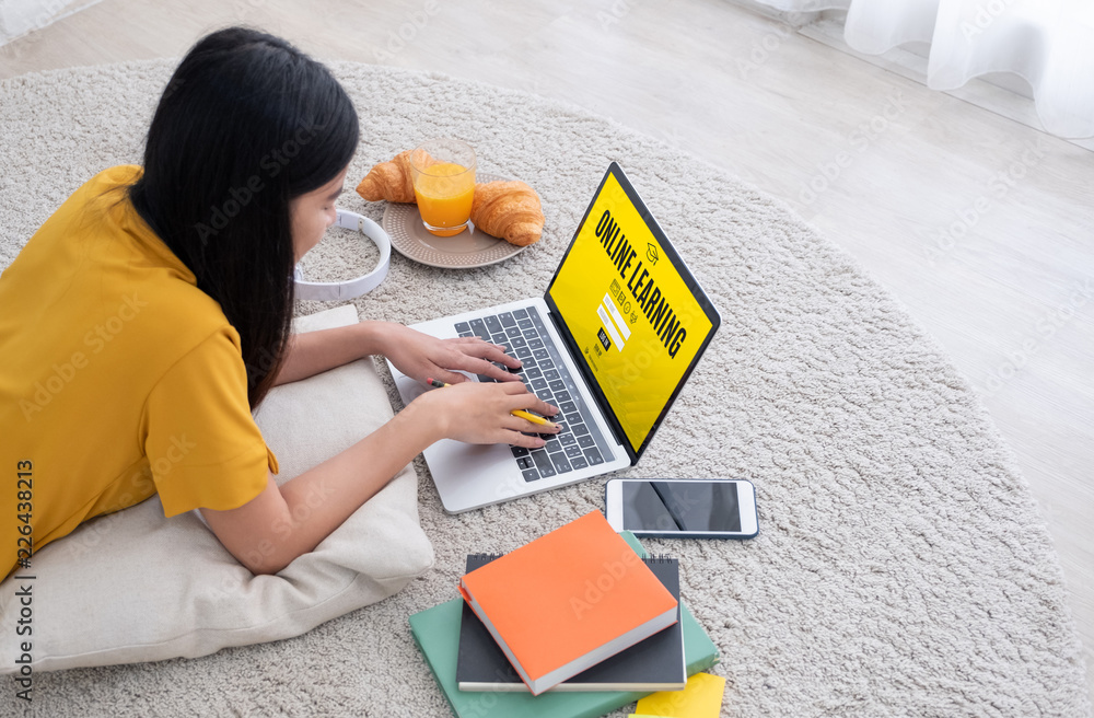 Poster asian female student log on to e-learing website on laptop computer at home.woman lying down on carp