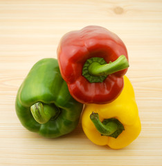 three peppers on wooden background