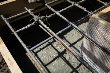 Close up wire mesh and wet cement in concrete floor pouring process