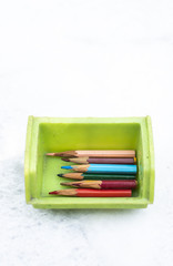 Naklejka premium Small pencils in a box and books