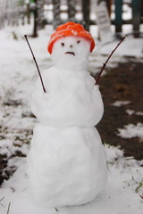 Winter fun - close up white snowman with their branches hands in the orange hat in the snow and the...