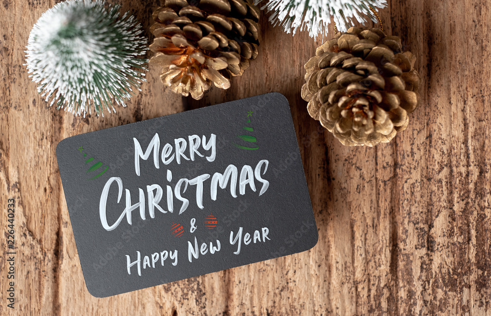 Poster top view of merry christmas and happy new year on blackboard with xmas tree and gold pine cone on gr