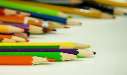 In selective focus of used color pencil on table,blurry light design background