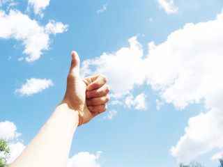 people and body parts concept - african woman hands showing thumbs up over blue sky and clouds background