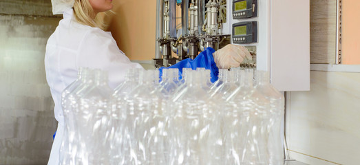 line of production of refined sunflower oil. Girl worker at a factory on a conveyor background with...