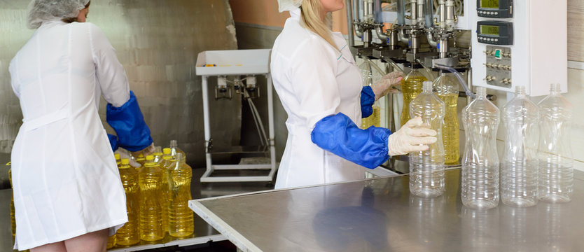 line of production of refined sunflower oil. Girl worker at a factory on a conveyor background with bottles of vegetable oil.